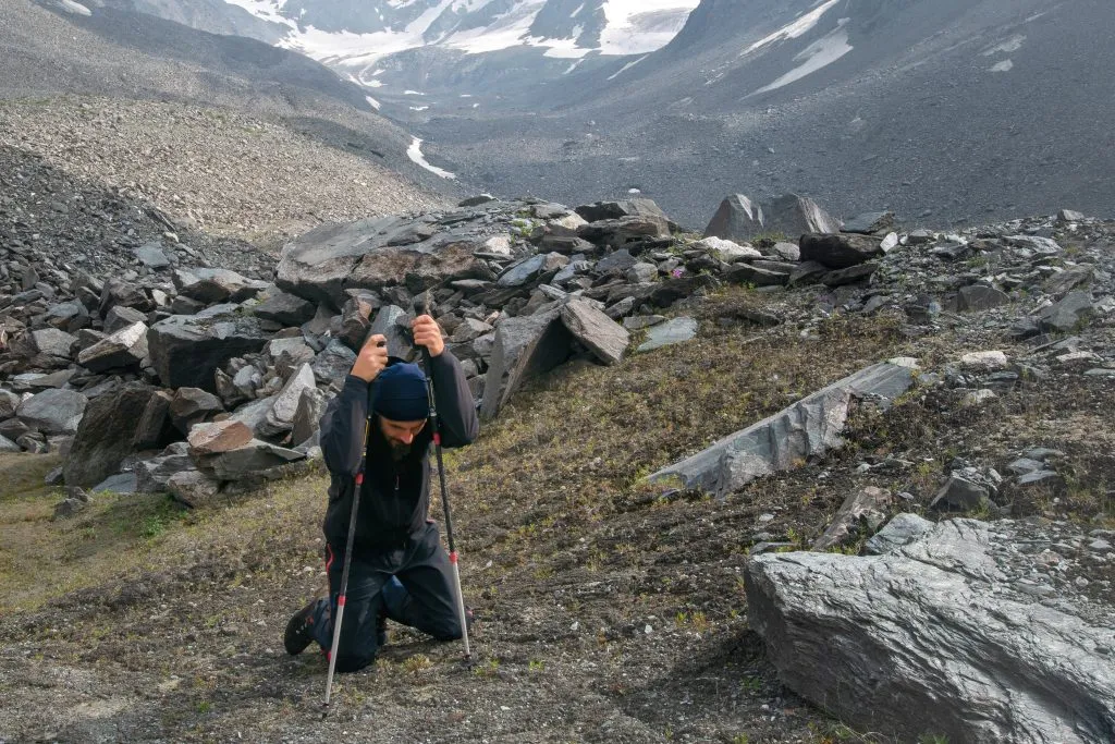 . Tired hiker with trekking poles in alpine landscape.